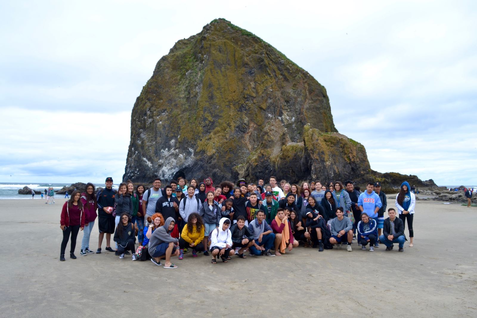students in front of giant rock at beach