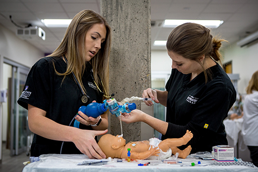 Two respiratory therapy students working on an infant patient in a laboratory