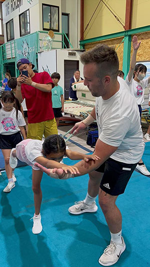 A young child performs a cheer stunt with a coach