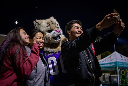 Three students pose for a selfie with Weber State's mascot