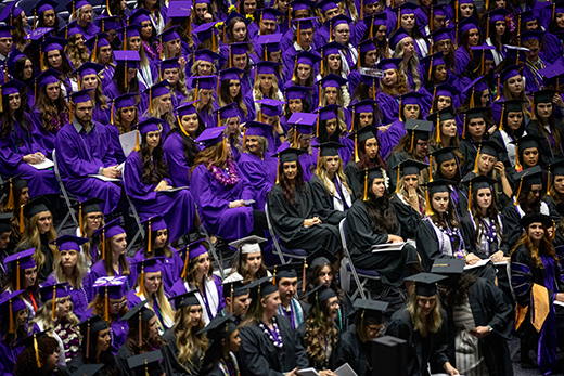 Graduates in purple and black robes gather for commencement ceremony