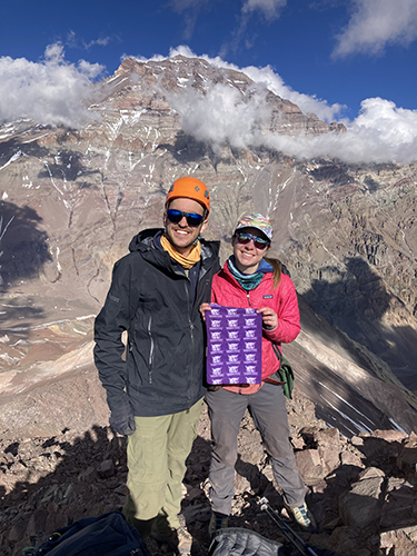 Elizabeth Balgord and Nicolas Pérez-Consuegra smile for a picture on Aconcagua. There are patches of snow on the mountain and no vegetation.