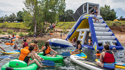 students on water with kayaks and slide