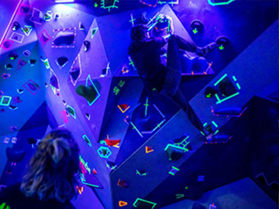 students on climbing wall with blacklights